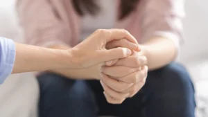 One hand placed on top of another hand to provide support.