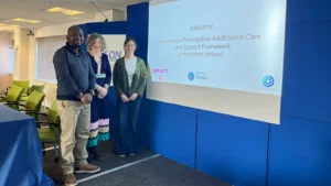 Obert Tawodzera, Barbara Campbell and Mary Webster, standing to welcome visitors to the Adult Social Care event in Northern Ireland.
