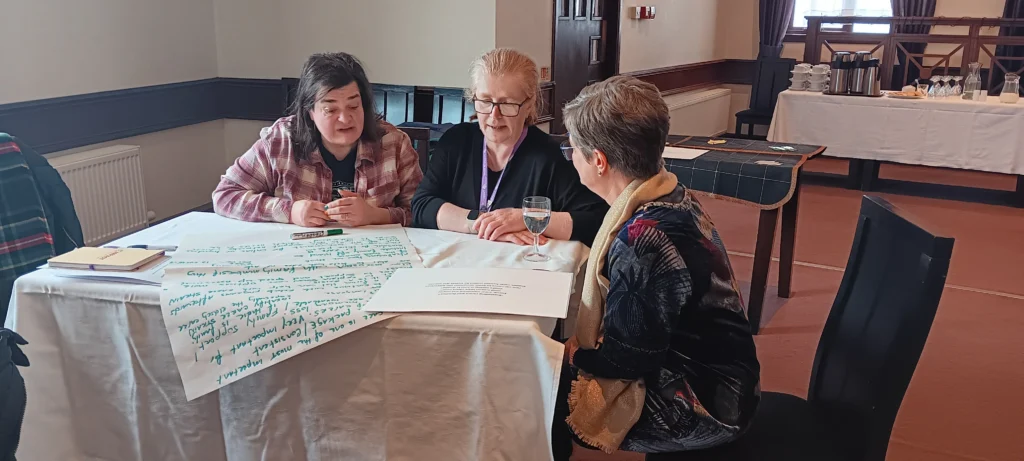 Three participants answering one of the world cafe questions in a group