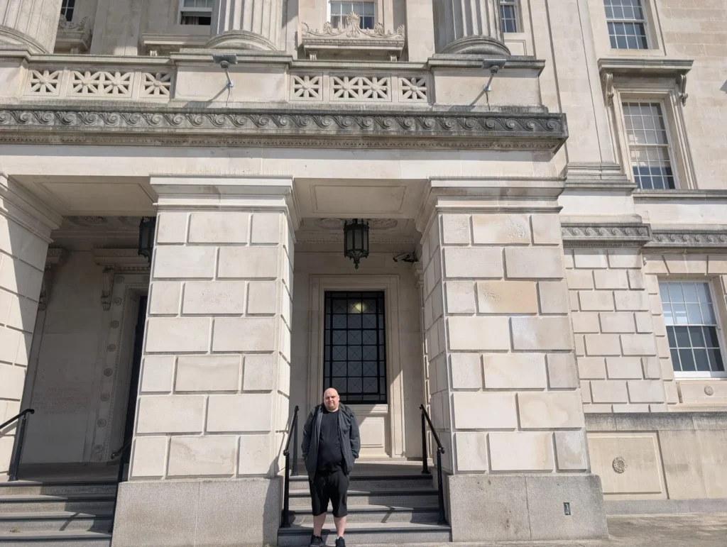 Ross stands outside of a building.